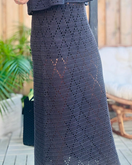 Person wearing a dark gray crochet outfit standing outdoors.